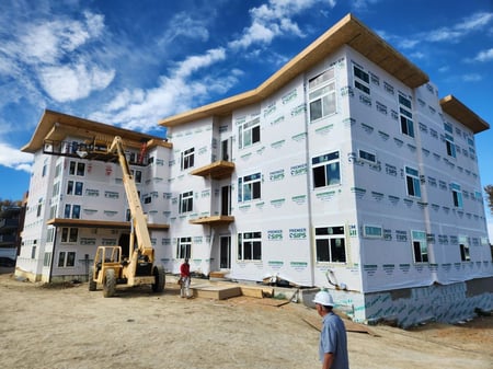 Multi-story apartment building under construction using Structural Insulated Panels (SIPs), showing a continuous, airtight building envelope designed for energy efficiency, durability, and long-term performance.